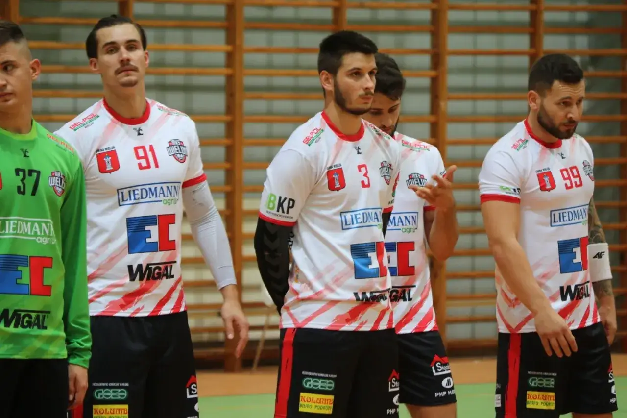 Zawodnicy MKS Wieluń w białych strojach z czerwonymi detalami, gotowi do gry.