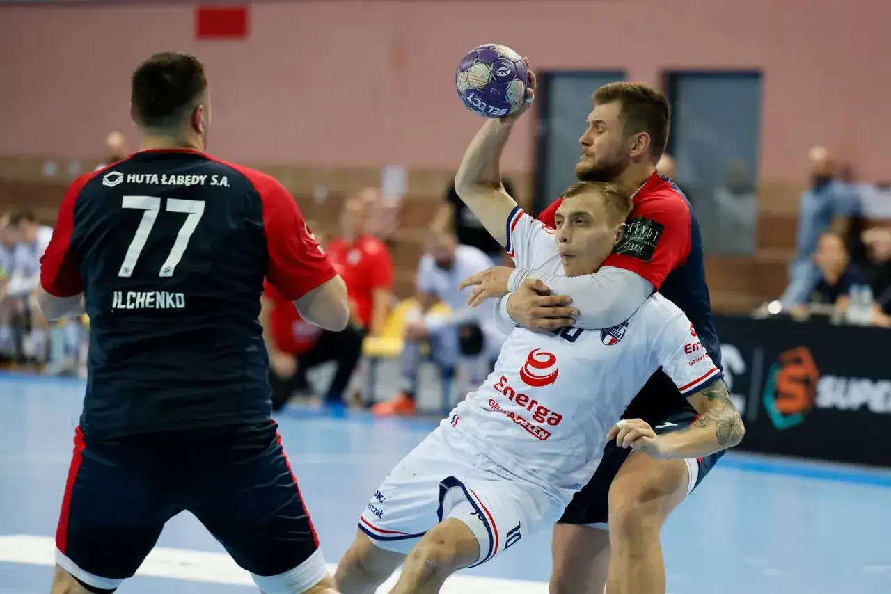 Bartosz Szczepanik w akcji, walczy o piłkę w meczu piłki ręcznej.