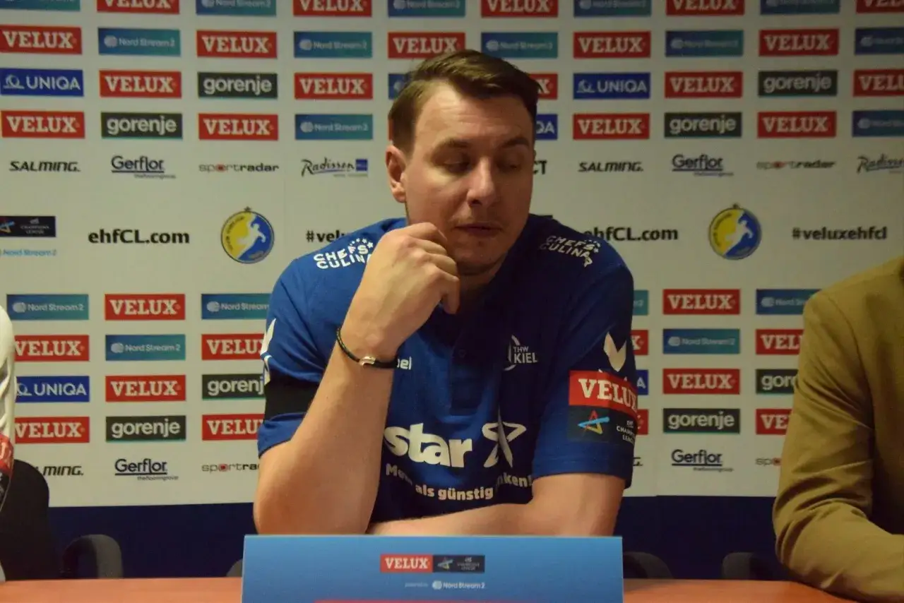 Filip Jicha, w niebieskiej koszulce THW Kiel, siedzi przy stole konferencyjnym.