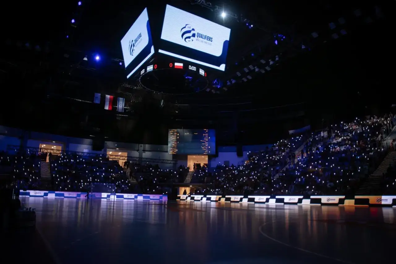 Widownia z zapalonymi telefonami czeka na rozpoczęcie meczu. Na ekranie logo 