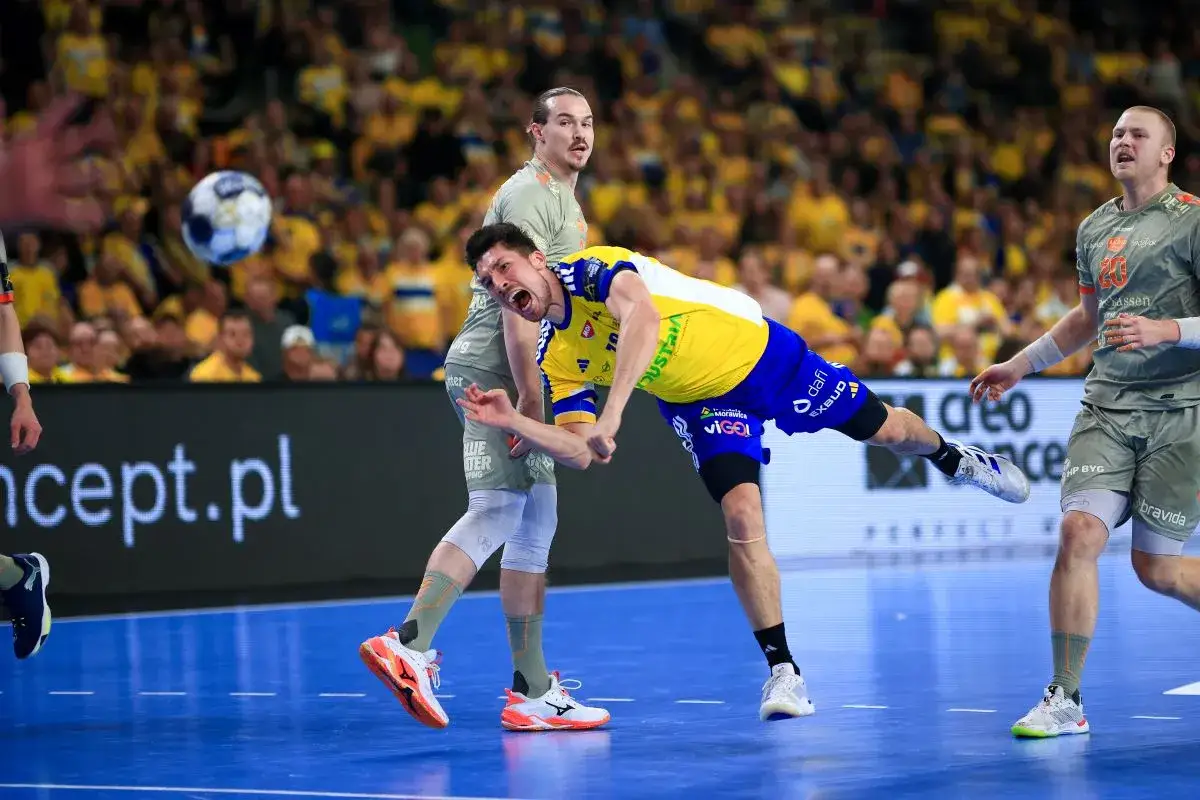 Piłka leci w stronę bramki, zawodnik Kielc w żółtej koszulce walczy o nią z graczem Aalborg.