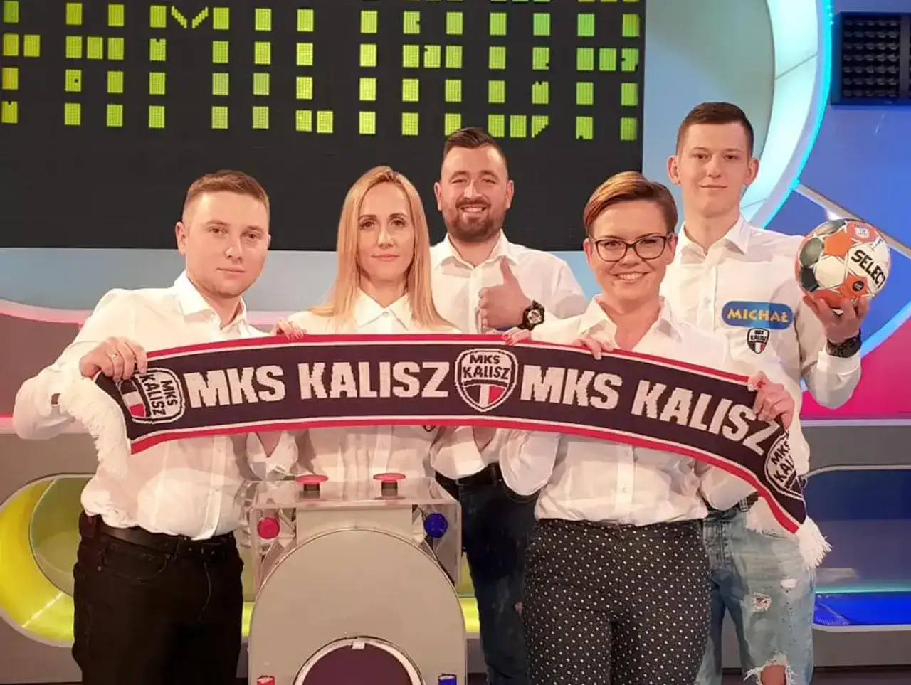 Drużyna MKS Kalisz świętuje sukces, trzymając szalik i piłkę.