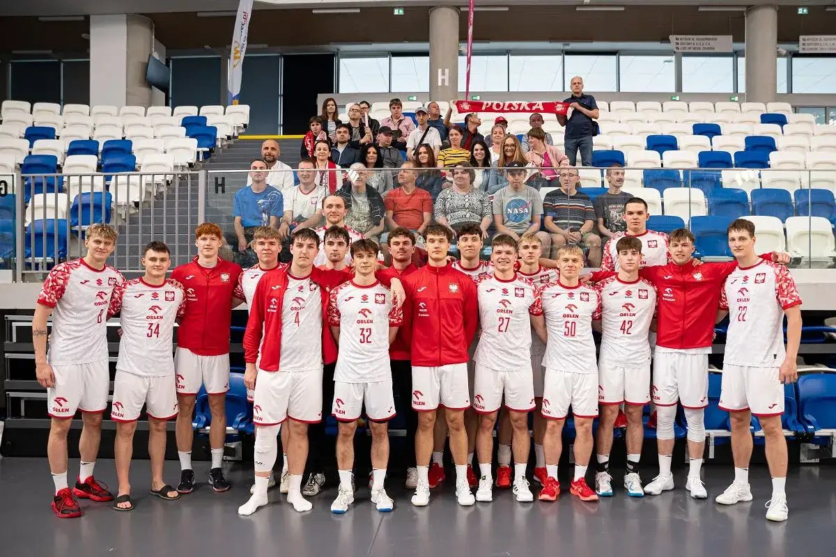 Młodzi piłkarze ręczni w strojach reprezentacji Polski, w tym Damian Borkowski, pozują do zdjęcia z kibicami na trybunach.