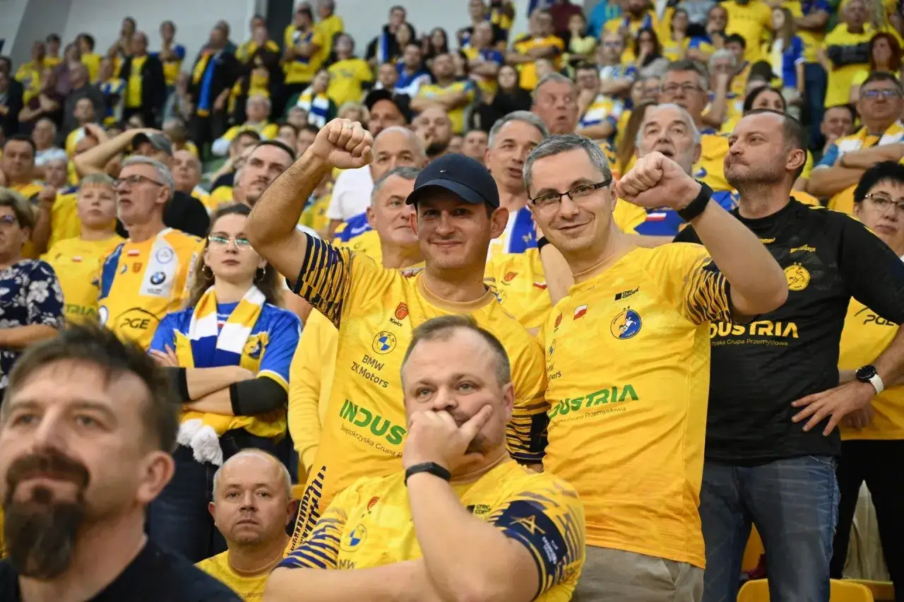 Fani w żółtych koszulkach z logo Aalborg Handball kibicują swojej drużynie.