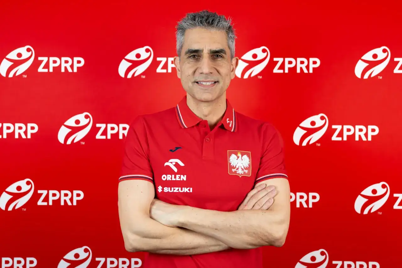 Trenerzy reprezentacji Polski w piłce ręcznej, w tym nowy selekcjoner, pozują na tle czerwonej ściany z logo ZPRP.