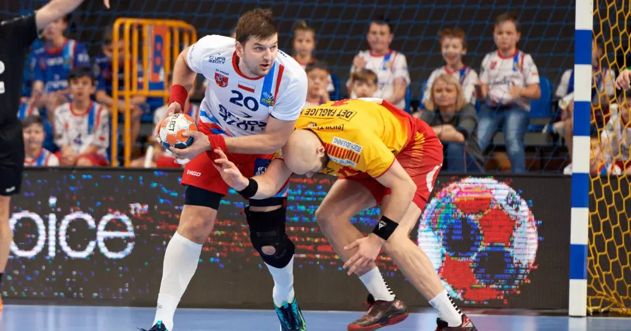 Dw&oacute;ch zawodnik&oacute;w gog handball walczy o piłkę. Jeden w białej koszulce z numerem 20, drugi w ż&oacute;łtej.