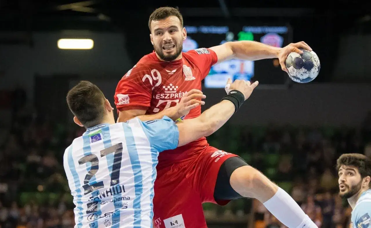 Nedim Remili w czerwonej koszulce z numerem 29, w akcji podczas meczu piłki ręcznej, próbuje rzucić piłkę do bramki.