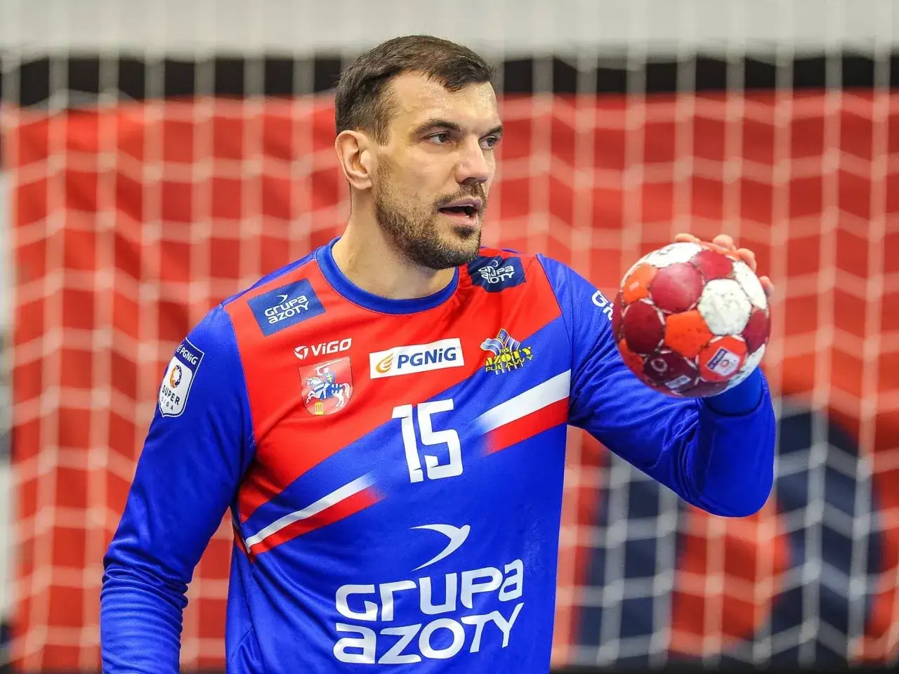 Michał Jurecki, zawodnik z numerem 15 na koszulce, trzyma piłkę do piłki ręcznej.