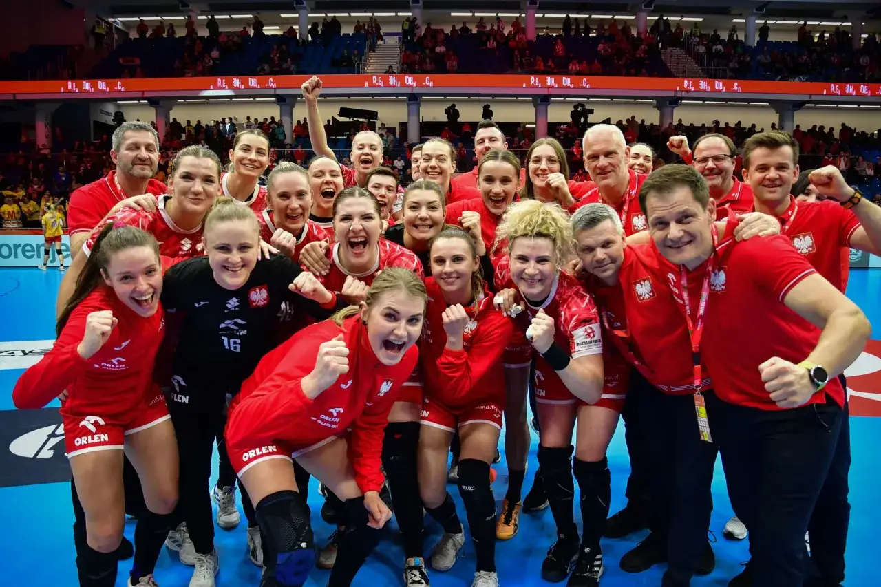 Radosna drużyna w czerwonych strojach świętuje sukces w super lidze kobiet. Uśmiechy i zaciśnięte pięści świadczą o wielkiej dumie.