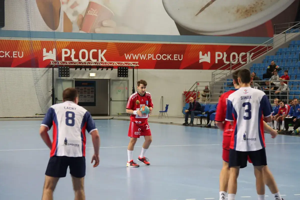 Piłkarz ręczny Michał Hoffmann w czerwonej koszulce z piłką w dłoni, na boisku w Płocku.