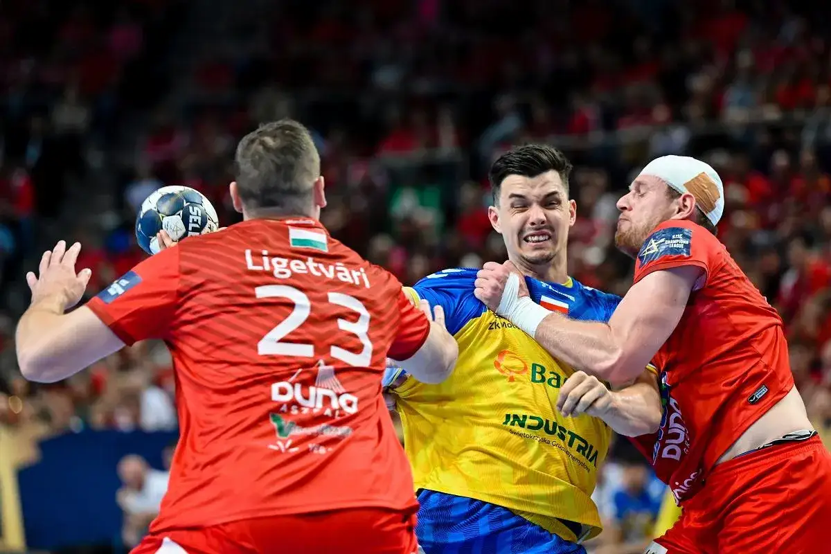Piłkarze ręczni Telekom Veszprem w akcji. Zawodnik w żółtej koszulce walczy o piłkę z dwoma przeciwnikami w czerwonych strojach.