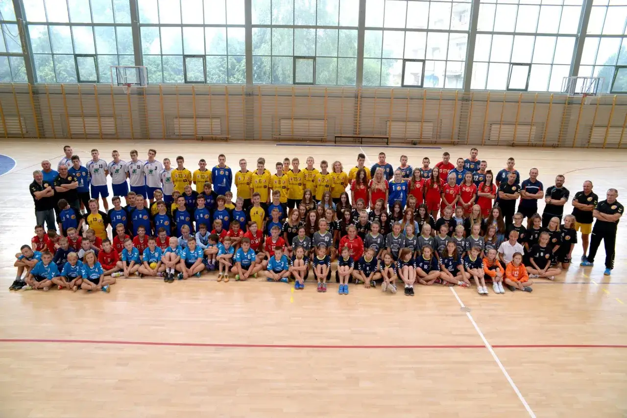 Drużyna Olimp Grodków pozuje do wspólnego zdjęcia w hali sportowej.