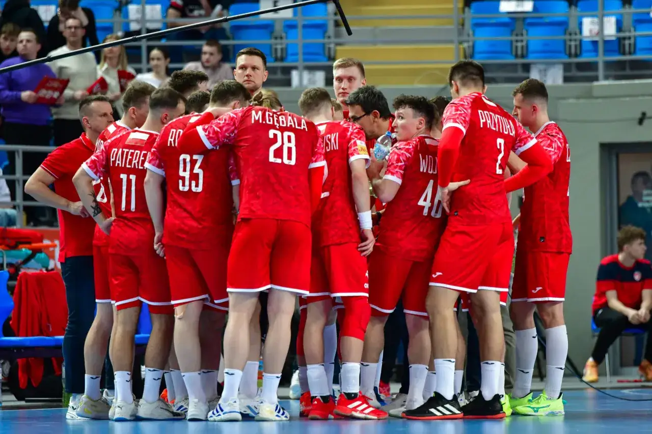 Drużyna piłki ręcznej w czerwonych strojach, z numerami na plecach, w skupieniu przed meczem. Polska kontra Niemcy - emocje gwarantowane!
