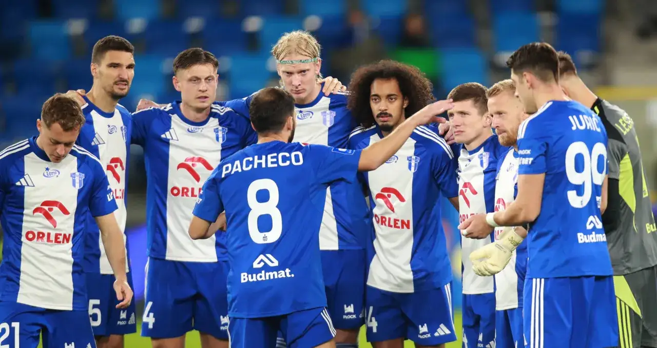 Piłkarze Wisły Płock w niebiesko-białych strojach, zebrani w kółku przed ważnymi rozgrywkami.