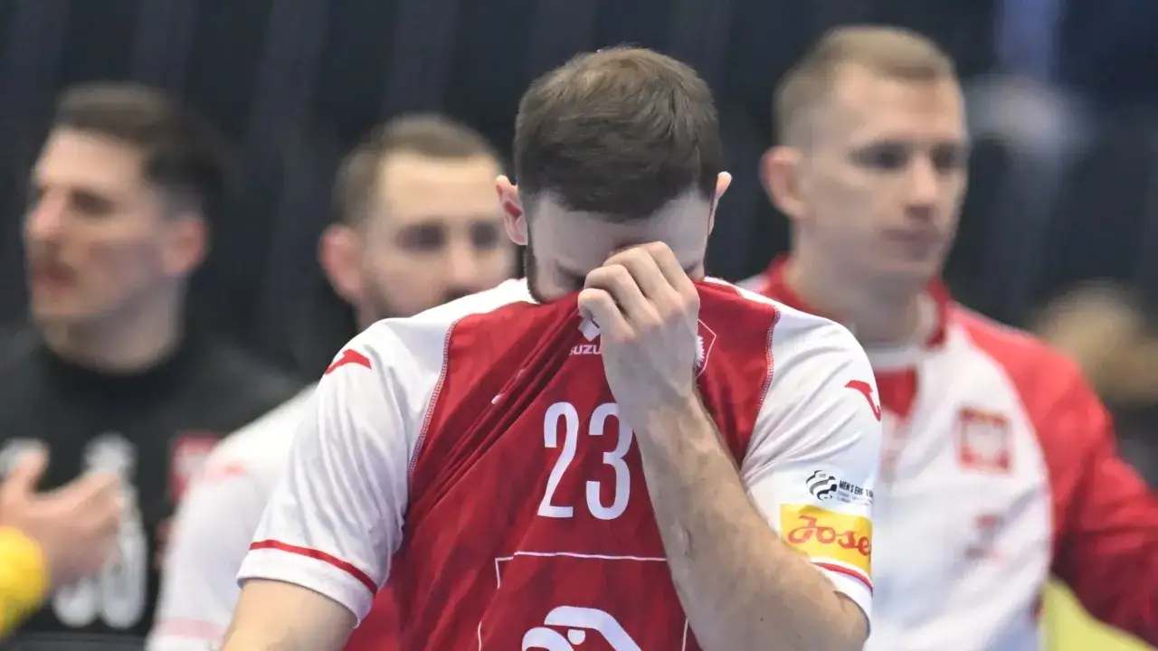 Piłkarz ręczny w koszulce z numerem 23 ociera łzy. W tle inni zawodnicy.