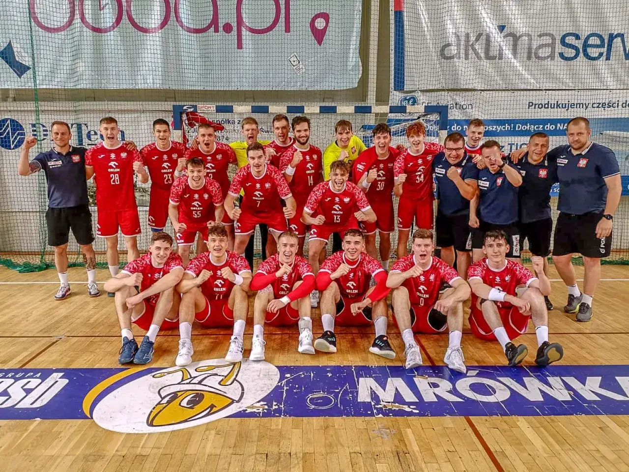 Drużyna piłki ręcznej w czerwonych strojach świętuje sukces na mistrzostwach.