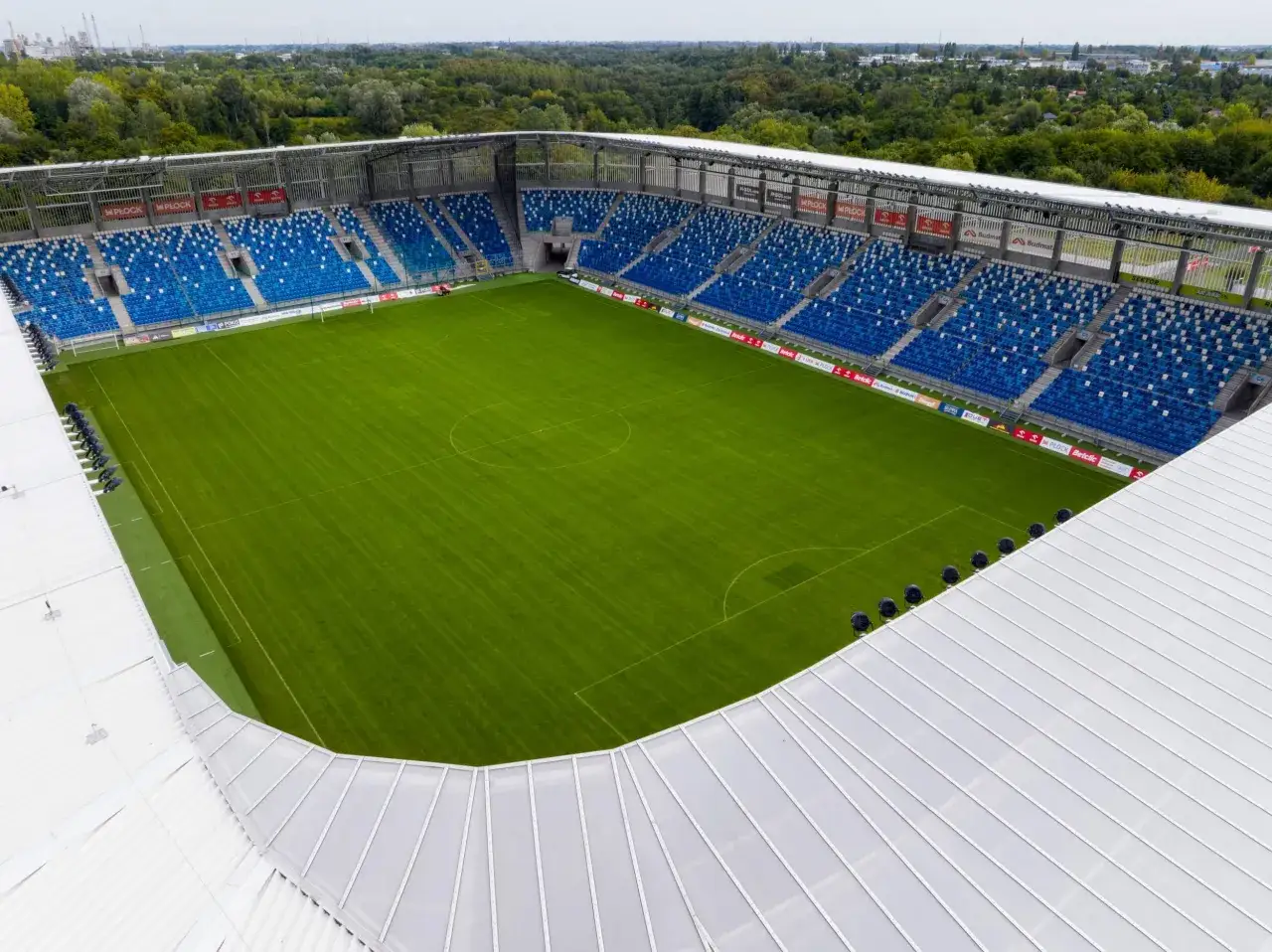 Pusta trybuna stadionu w Płocku, gotowa na kolejny mecz. Zielona murawa czeka na piłkarzy.