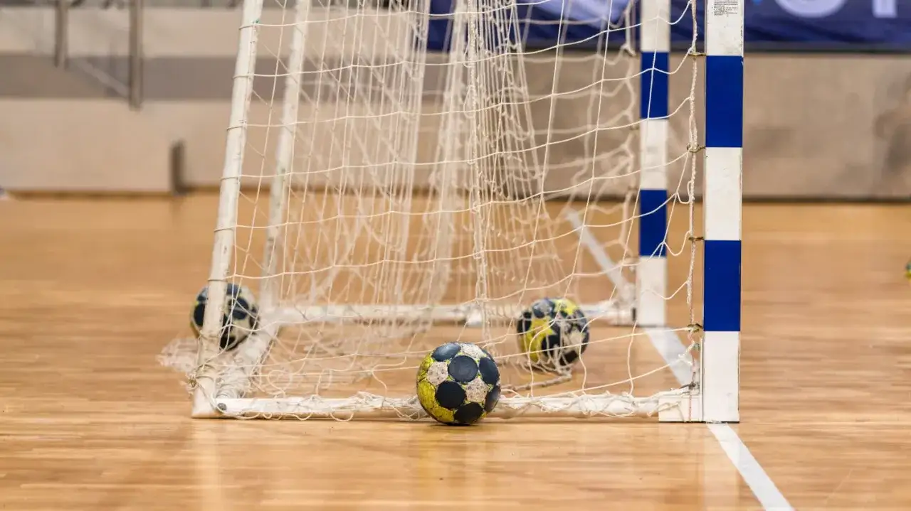 Piłki do piłki ręcznej leżą przy bramce na hali sportowej. Może to być trening przed meczem w Hiszpanii.