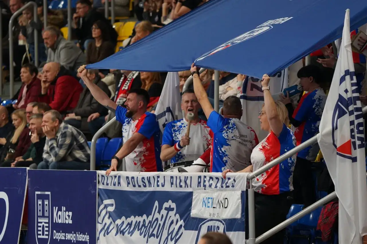 Kibice MKS Kalisz z bębnem i flagami dopingują drużynę.