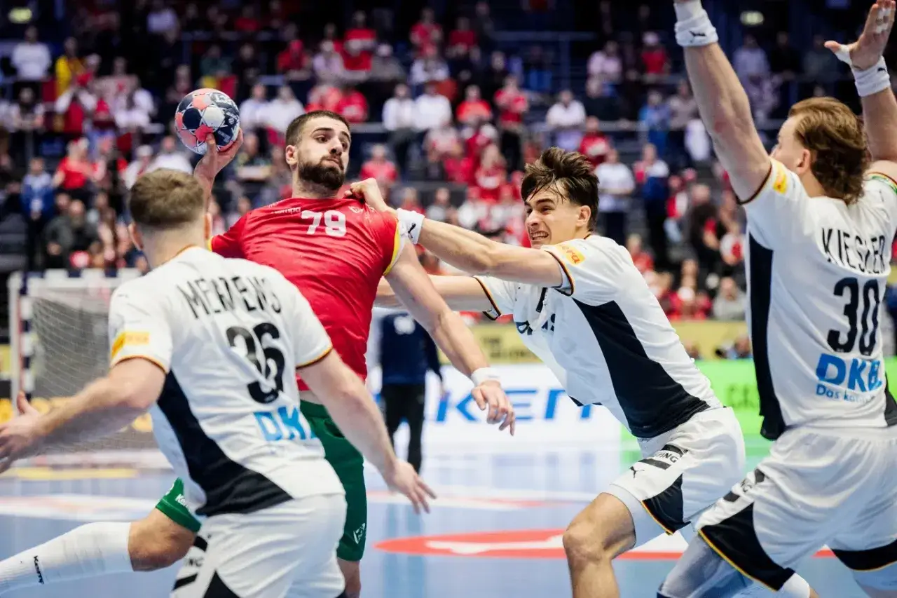 Zacięta walka na boisku! Zawodnik w czerwonej koszulce z numerem 79 próbuje rzucić piłkę, ale obrońcy z Niemiec, w białych strojach, skutecznie go blokują. Emocje w piłka ręczna Niemcy sięgają zenitu!