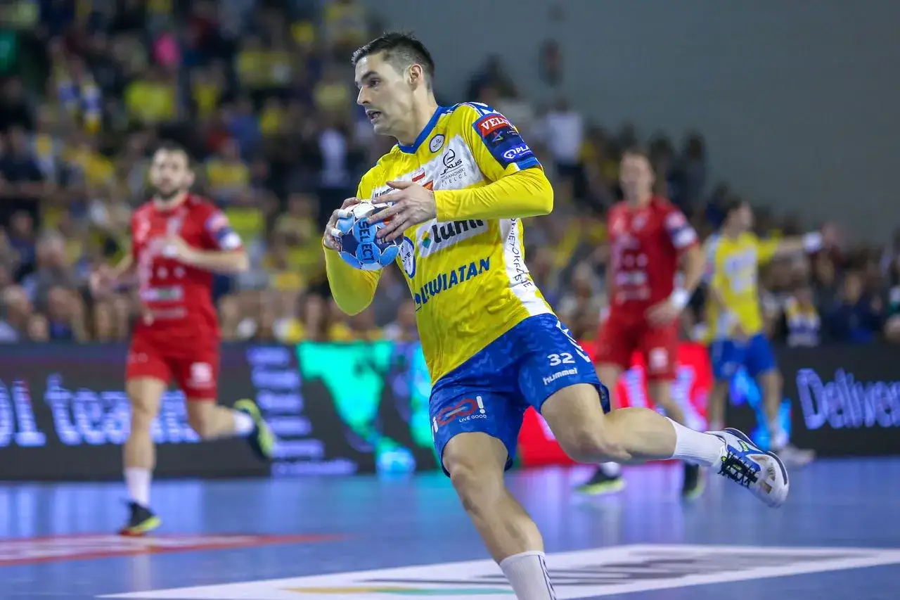 Piłkarz ręczny Angel Fernandez w żółtej koszulce z niebieskimi spodenkami biegnie z piłką.