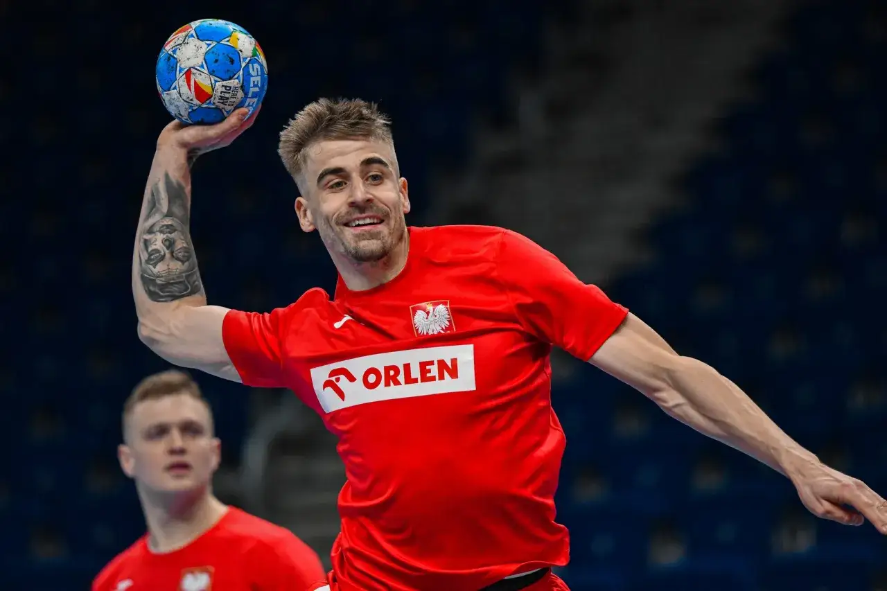 Daniel Reznicky, zawodnik z tatuażem na ramieniu, rzuca piłką do piłki ręcznej.