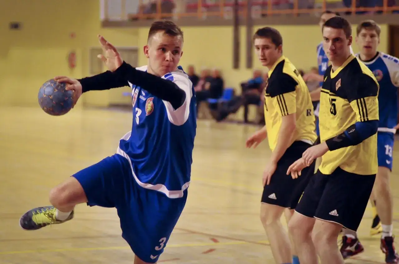 Michał Hoffmann w akcji, rzuca piłką do bramki podczas meczu piłki ręcznej.