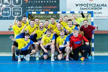Drużyna Unii Tarnów piłka ręczna świętuje zwycięstwo. Radośni zawodnicy w żółto-niebieskich strojach pozują do wspólnego zdjęcia.