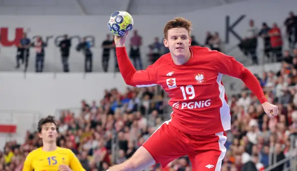 Jan Czuwara w akcji, rzuca piłką do bramki. Zawodnik w czerwonej koszulce z numerem 19.