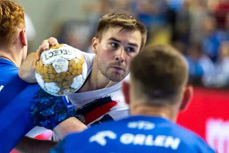 Piłkarz ręczny Luc Steins z piłką w ręku, otoczony przez obrońców.